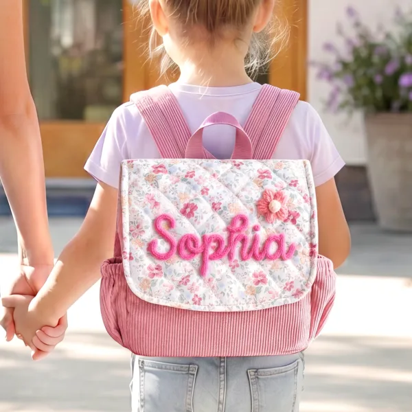 On-body Back View of a Toddler Girl Wearing Nameli Personalised Pink Corduroy Backpack with Quilted Floral Flap